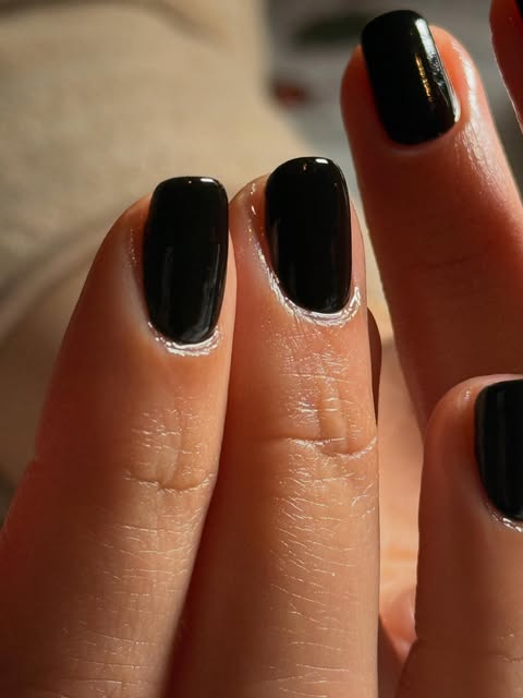 Close-up of glossy black nails with softly squared tips.